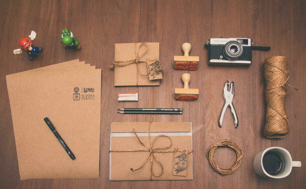 Flatlay photograph of brown printer paper, mug, pencil, and camera.