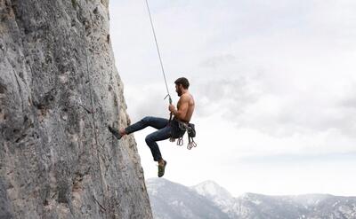 Strong man climbing on a mountain with safety equipment