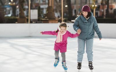 Kid and mother ice skating together.