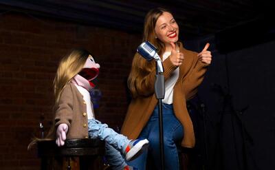 Female ventriloquist during show with puppet.