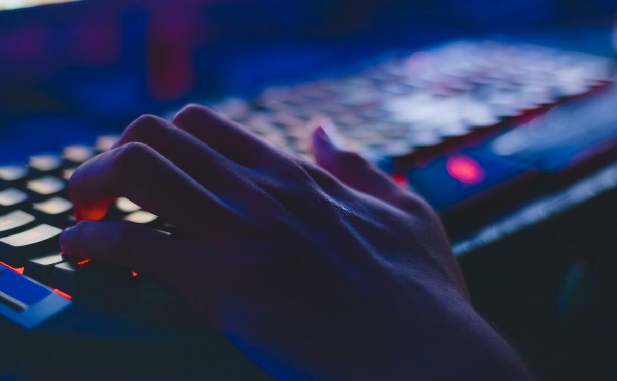A person is using a keyboard in a dark room.