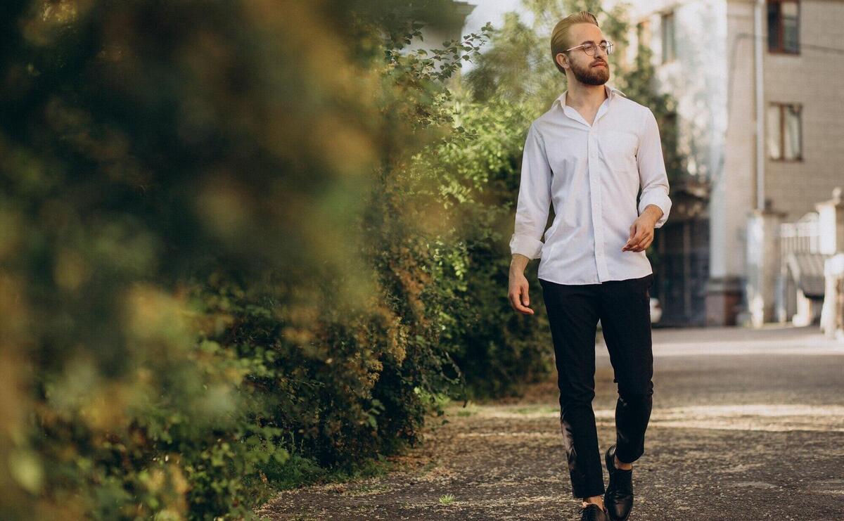 Portrait of young bearded man wearing spectacles and walking in park