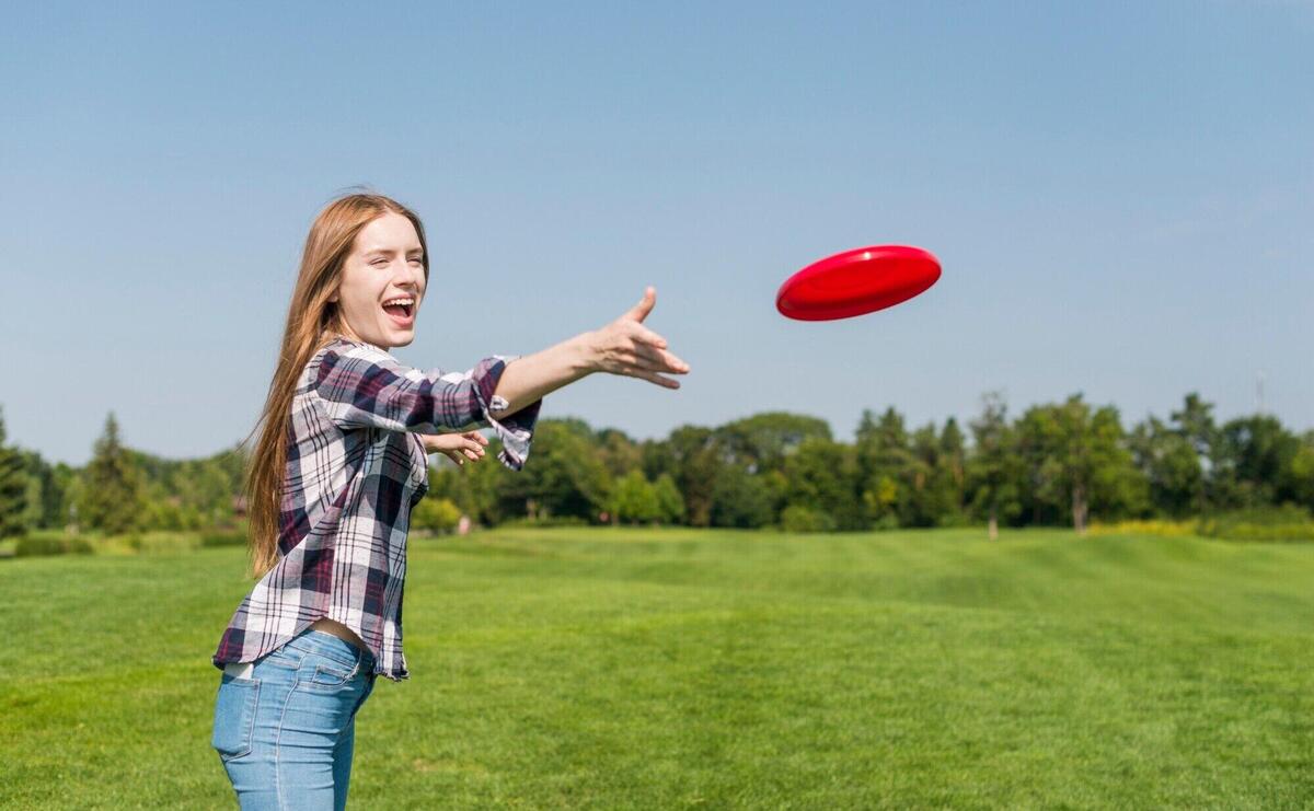 Blonde girl throwing a red frisbee