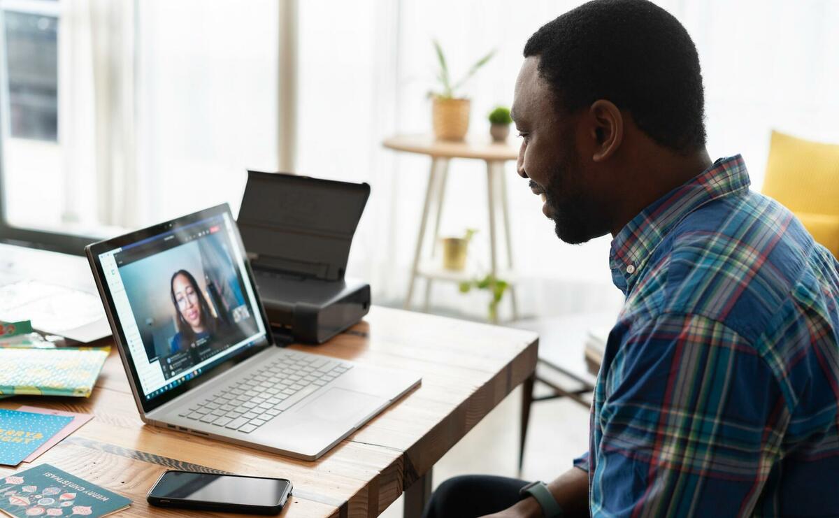 One person is using a laptop to video chat with a colleague.