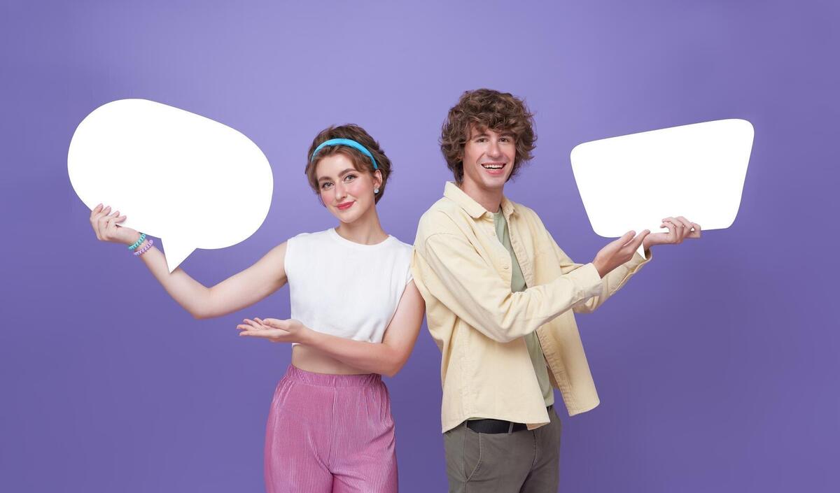 Happy teen couple holding blank speech bubbles on purple background