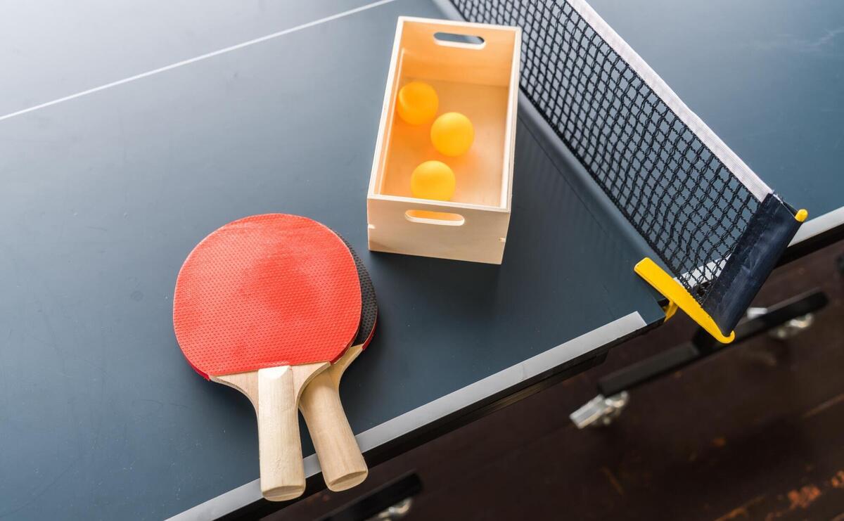 Table tennis paddles and balls ready for play on a blue table.