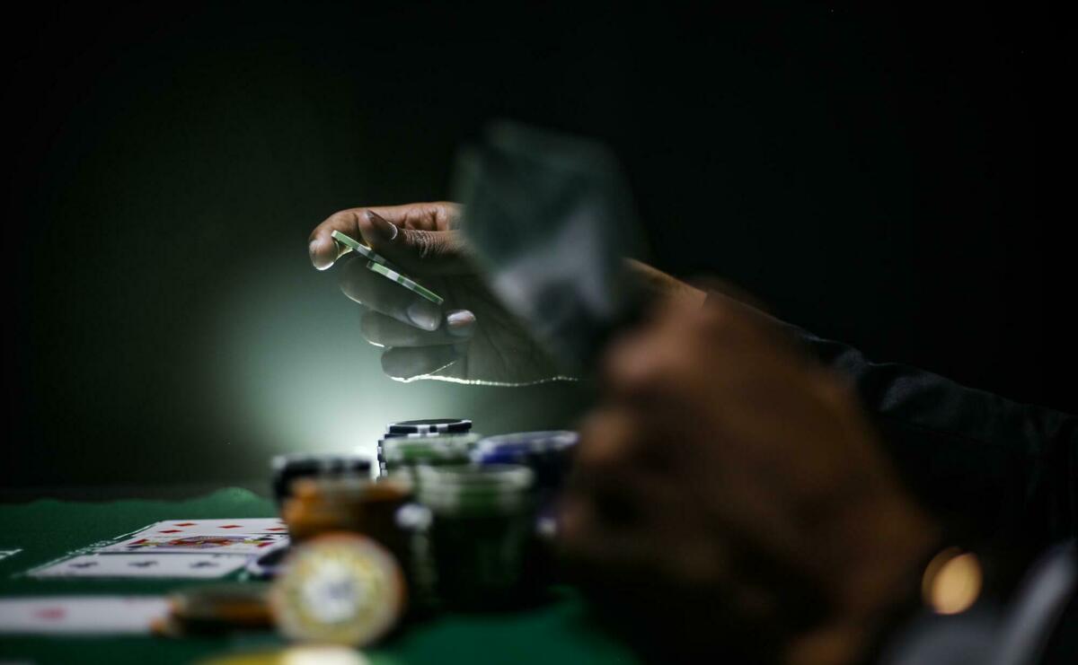 A person is using casino chips at a poker table.