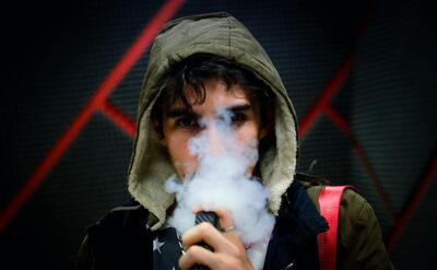 Young man is vaping in hoodies