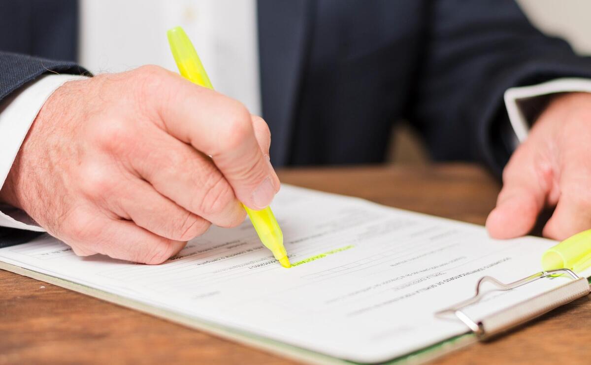 Businessman highlighting text on a document with a yellow marker.