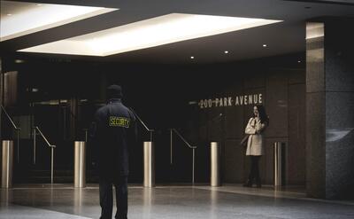 A security guard is standing in front of a hotel.