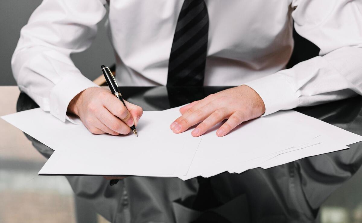 Professional in white shirt signing a document.