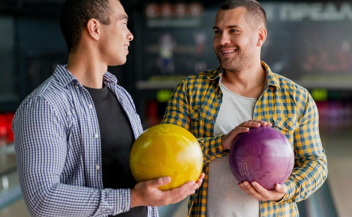 Happy men holding a colorful bowling balls