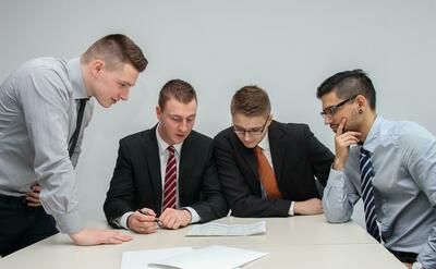 Four men looking to the paper on table.