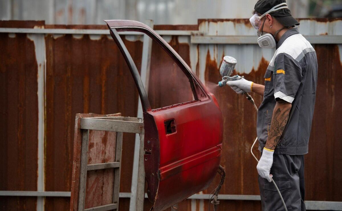 Medium shot man spraying powder paint on car door