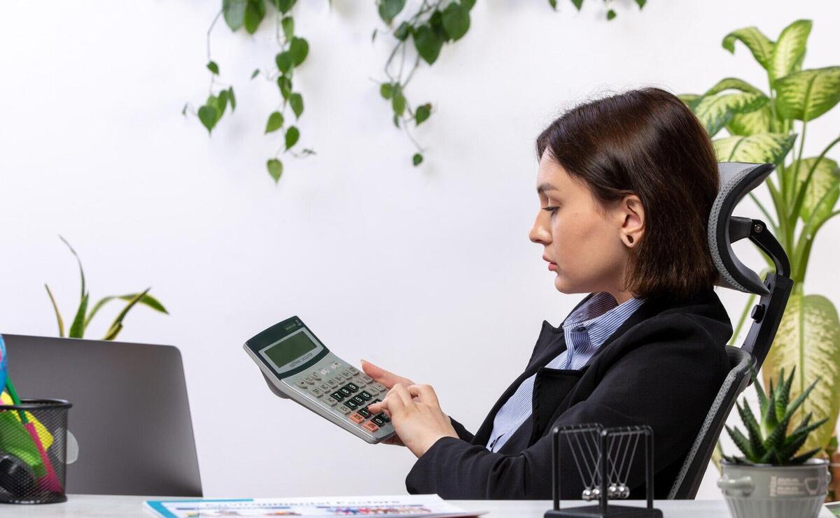 A front view beautiful young businesswoman in black jacket and blue shirt working with calculator in front of table business job office