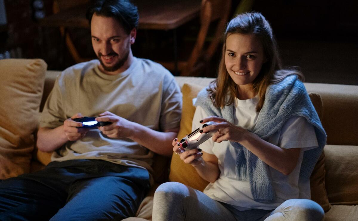 A couple is playing computer games on a couch