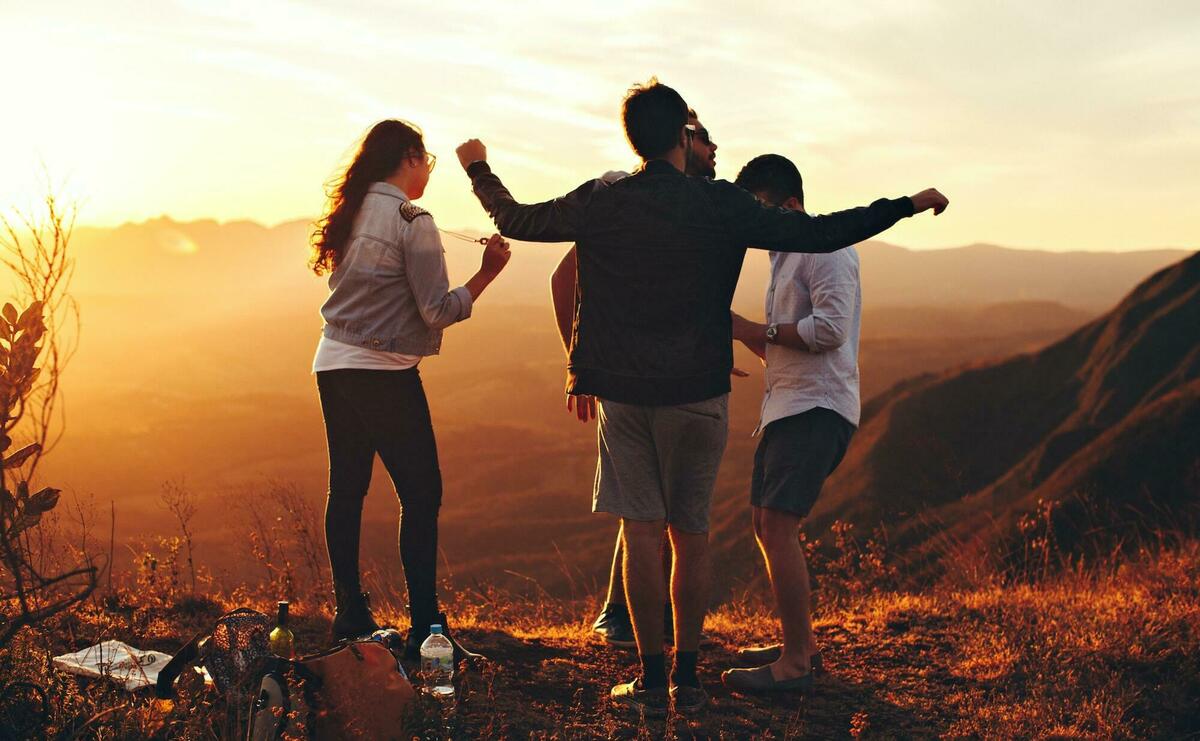 A group of young people dancing on the top of a hill.