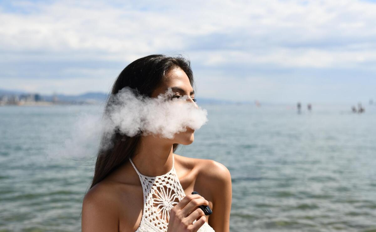 Young woman is vaping on the beach