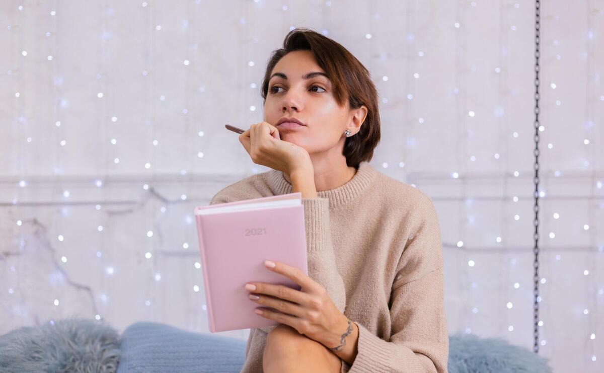 Woman in comfy sweater and wool socks at home sit on bed at winter time.