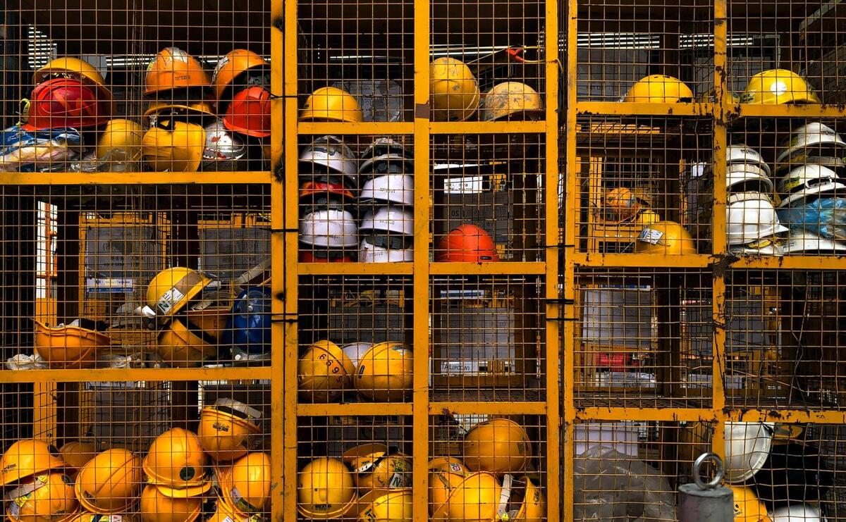 A rack filled with lot of construction helmets.
