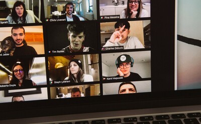 A computer screen shows an online meeting, all of the team members are shown on a small web-camera picture.