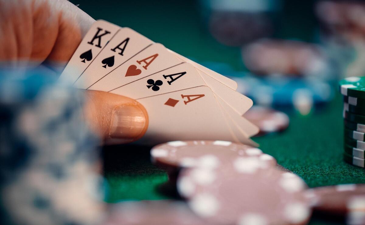 Hand holding 4 aces at a poker table