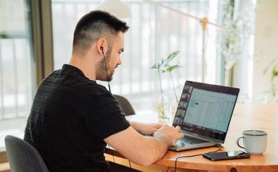 A man in black t-shirt using a laptop.