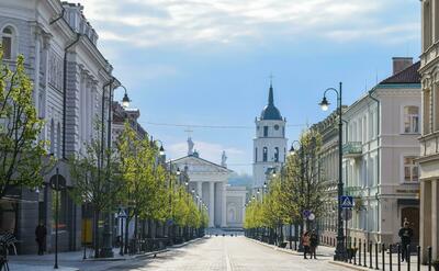A picture of Vilnius, a nice a clean street towards a white and gray tower.