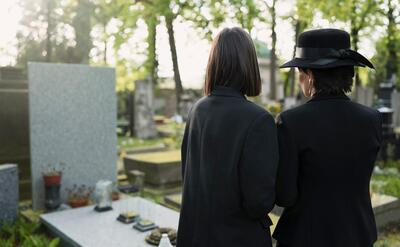Mourning mother and daughter at a grave in the cemetery