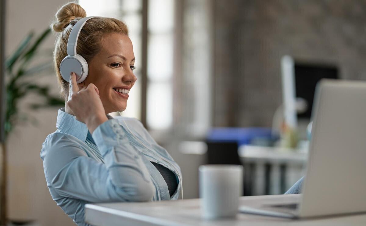 Smiling businesswoman relaxing with music over headphone while using computer in the office