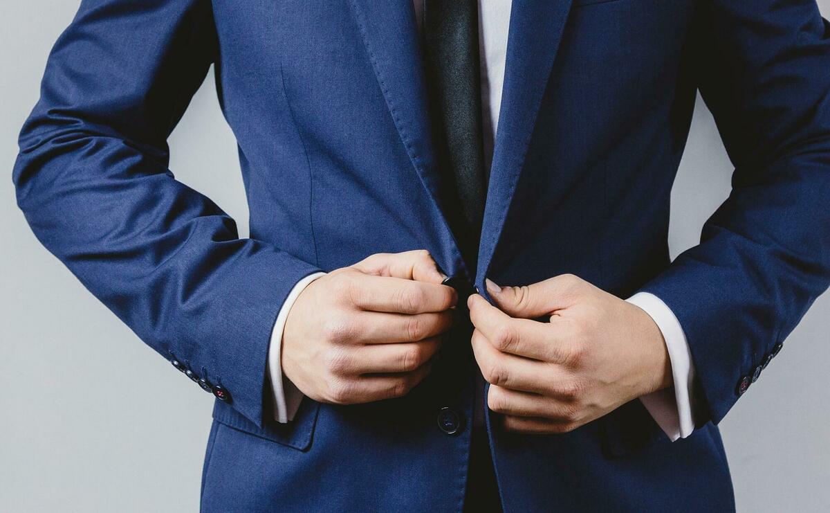 A businessman is buttoning his suite.