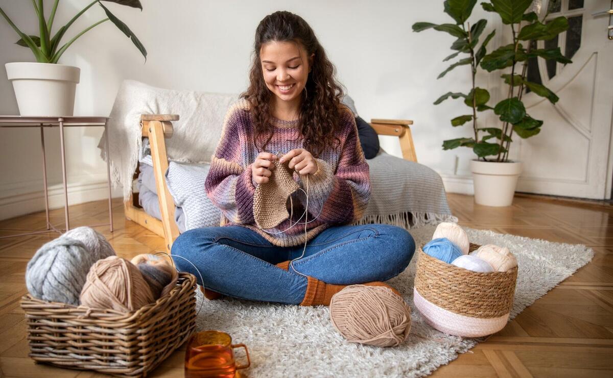 Y happy woman knitting at home.