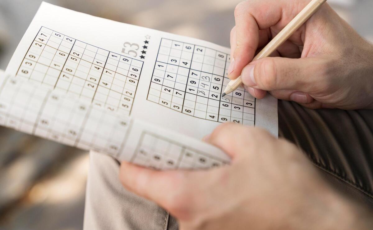 Man enjoying a sudoku game on paper.