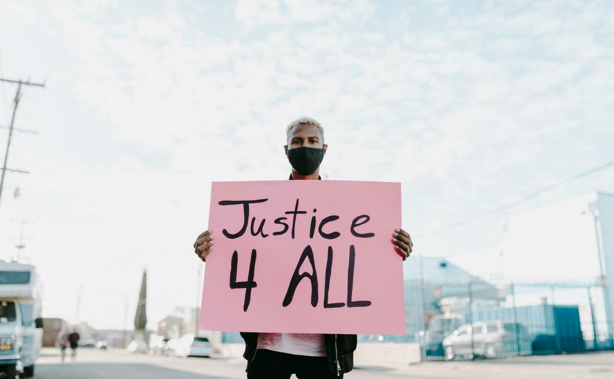 A young man is standing with a "Justice 4 all" sign.