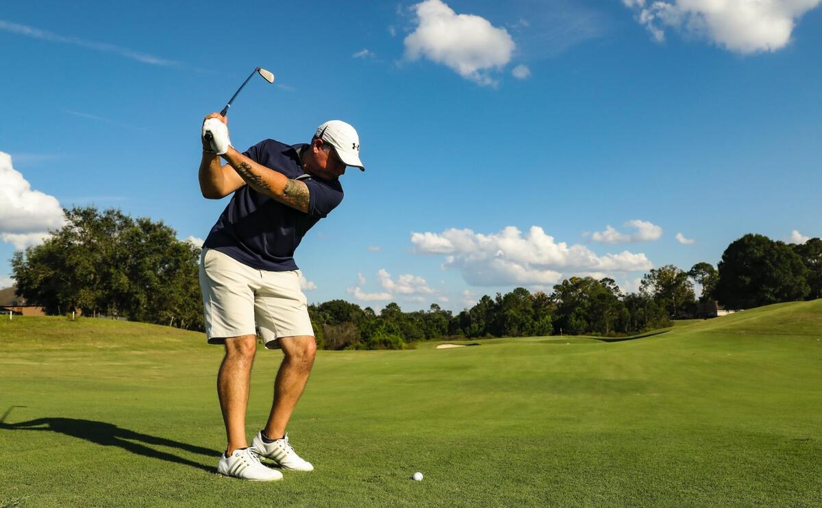 A golfer is swinging his club to hit the ball.